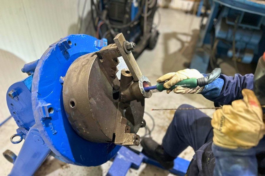 Operario trabajando en la superficie interna de un componente industrial crítico en las instalaciones de Asimer Group