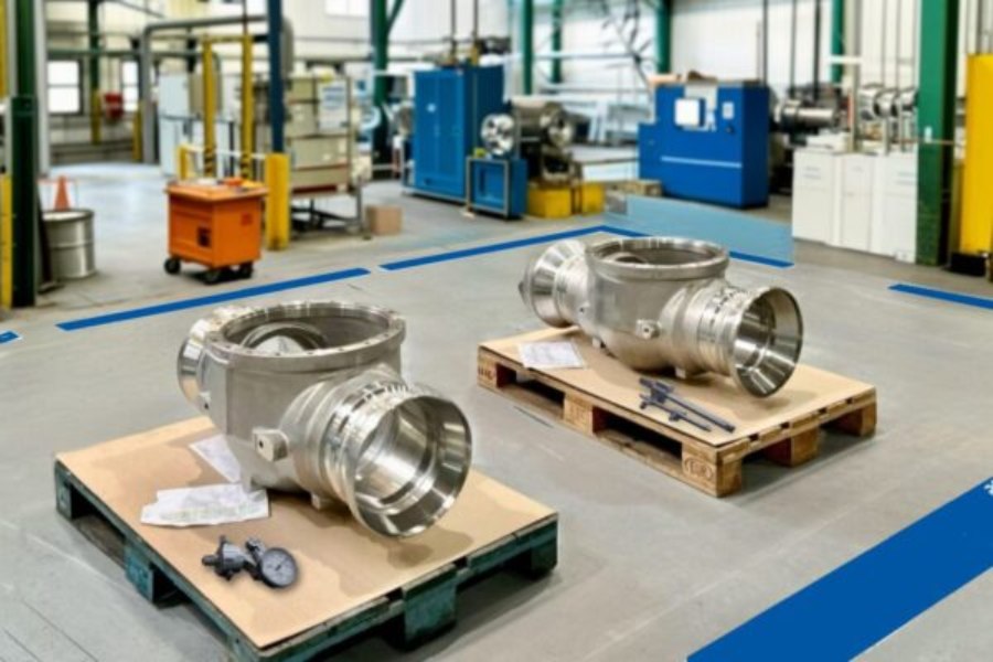 Large valve bodies on pallets during dimensional inspection using a caliper and micrometer at Asimer Group to reduce industrial metrology measurement errors.